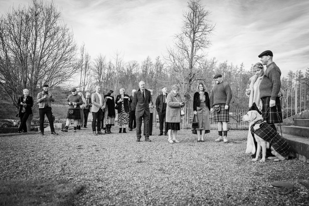 Wedding guests gathered outdoors on a winter day for a group photo.