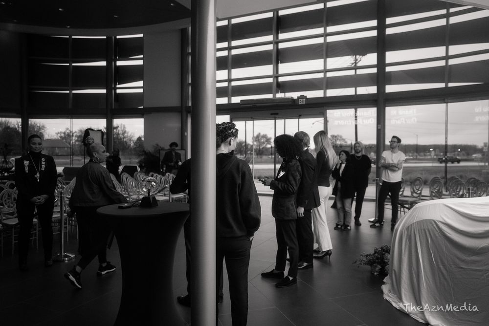 People mingling at an elegant indoor event with floor-to-ceiling windows.