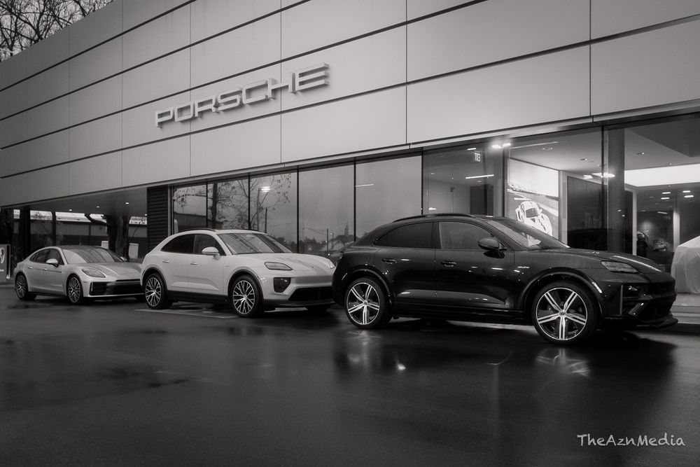 Porsche dealership exterior at night with luxury vehicles on display.