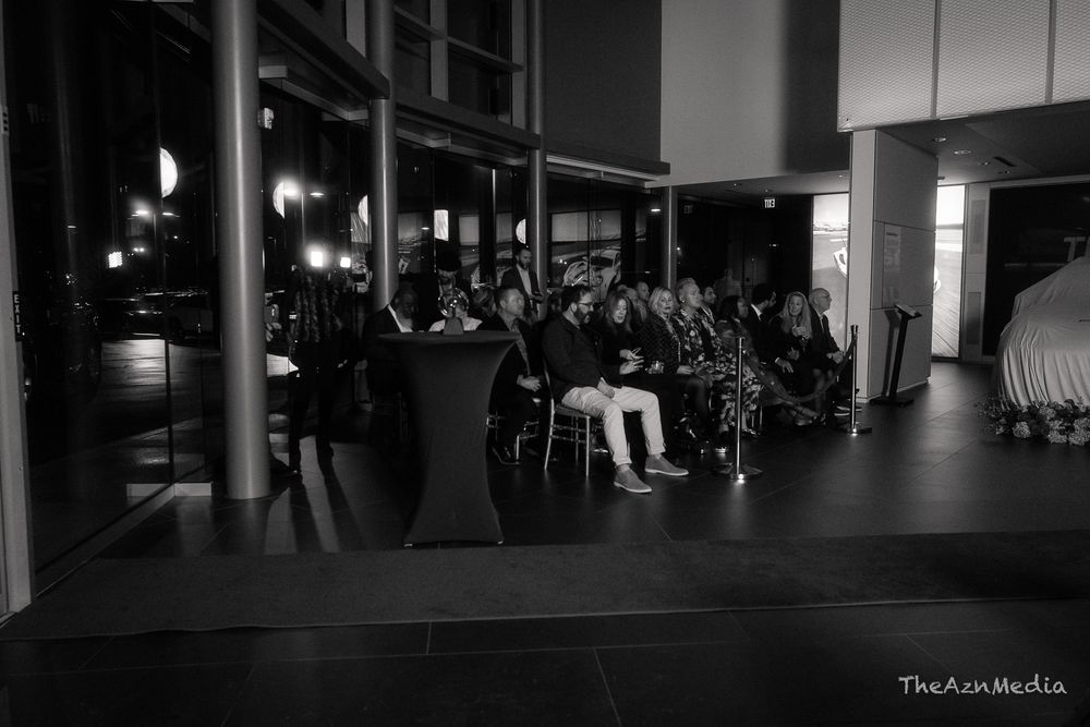 Audience members seated in rows at a darkened indoor event venue.