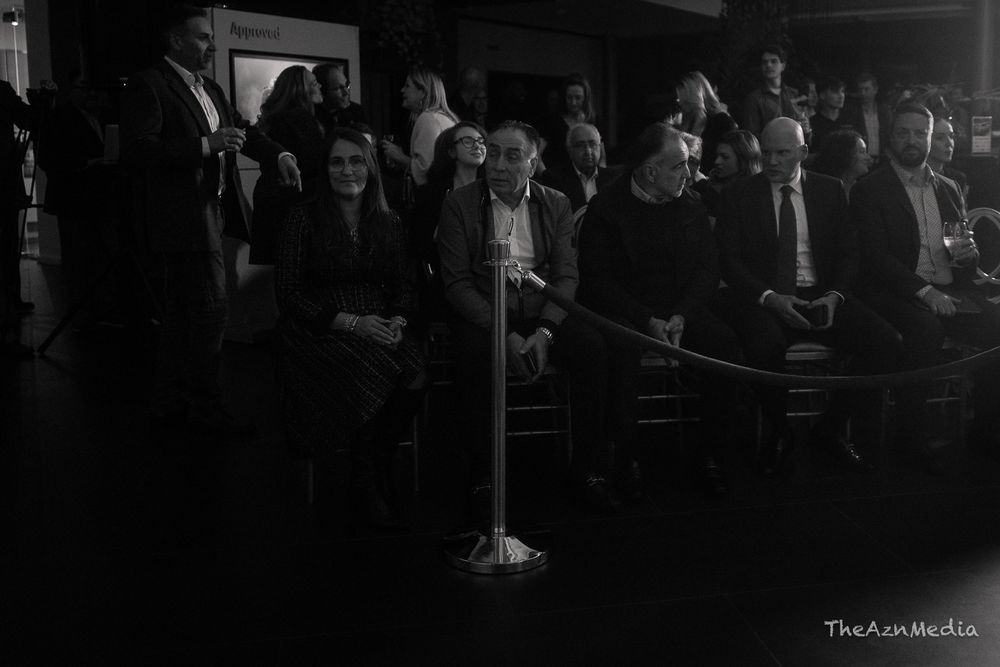 Crowd of people standing in a dimly lit venue space during an event.