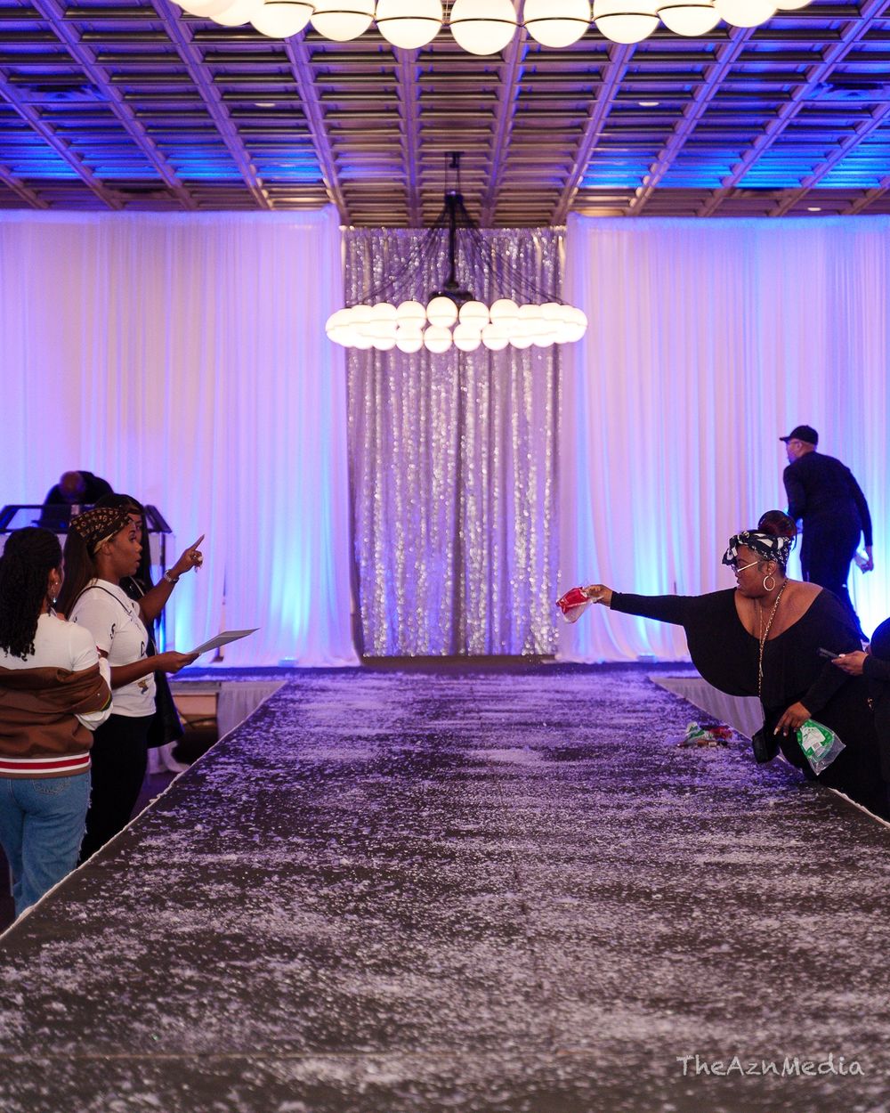 Photographers capturing shots in purple-lit event space with silver curtain backdrop.