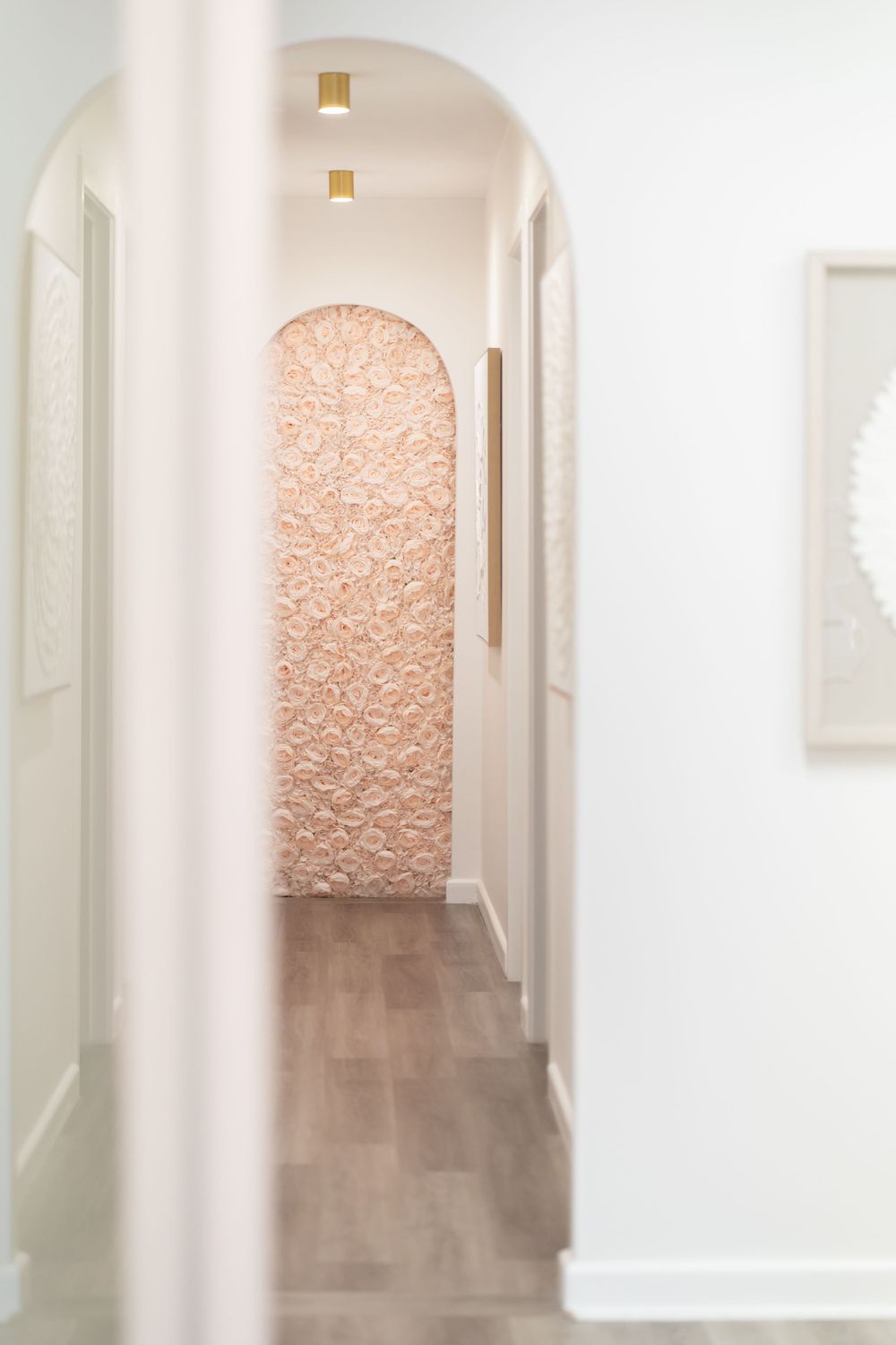 Modern hallway with arched doorway and textured peach accent wall.