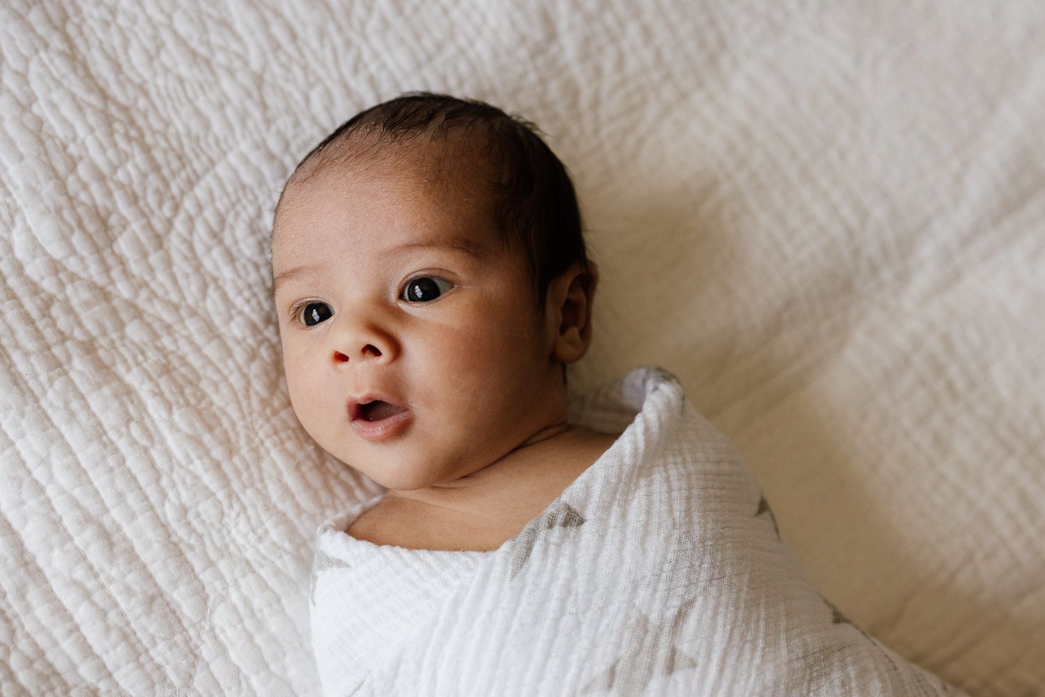 Swaddled baby boy at newborn photo session at in in-home lifestyle newborn photoshoot