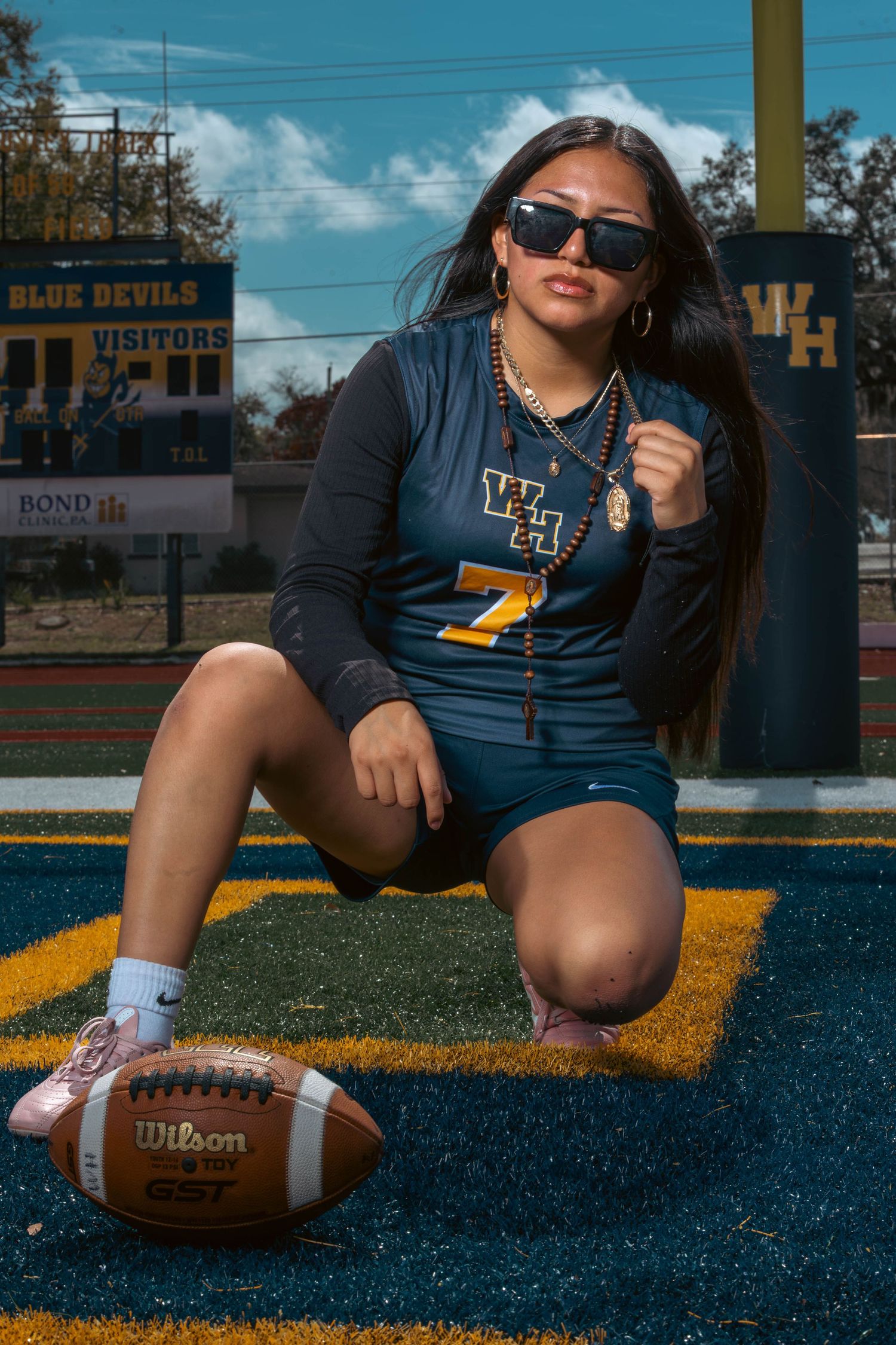 Female athlete poses with Wilson football on Blue Devils field wearing jersey number 7.