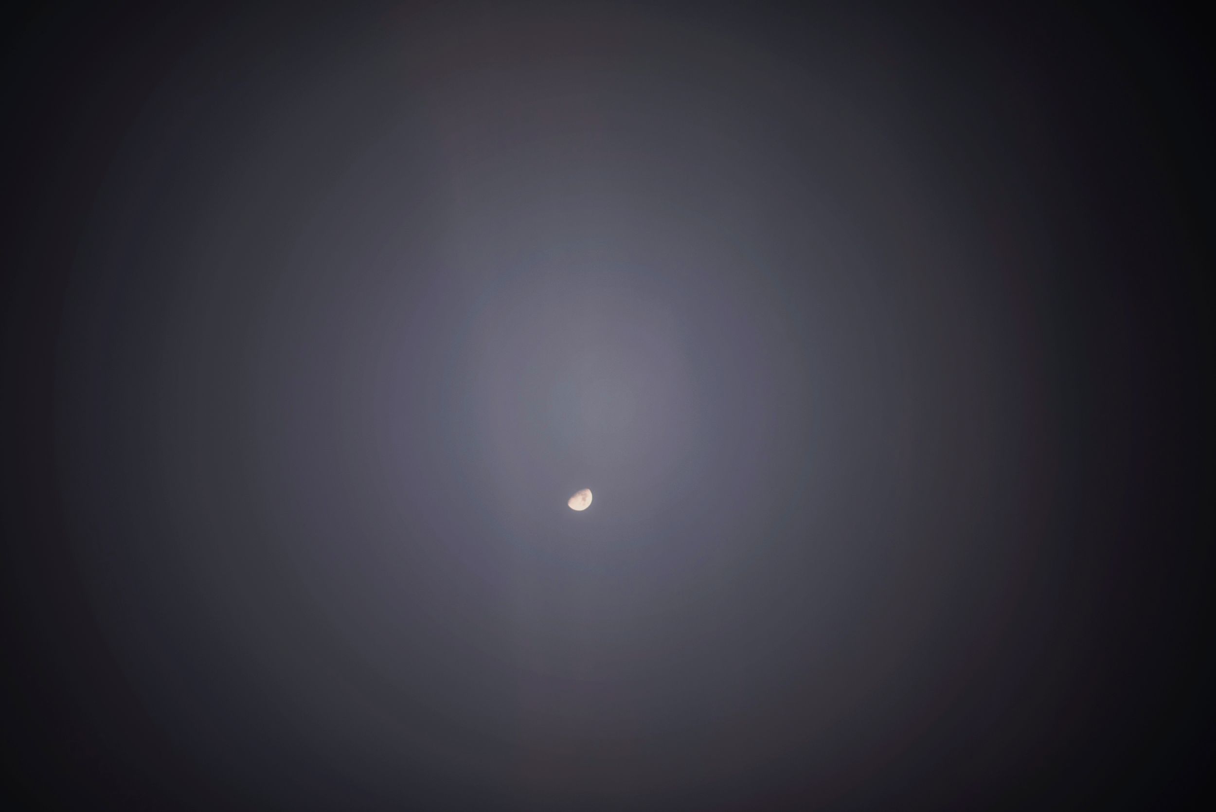 A bright speck of light glows in a misty, dark sky creating a hazy ethereal effect.