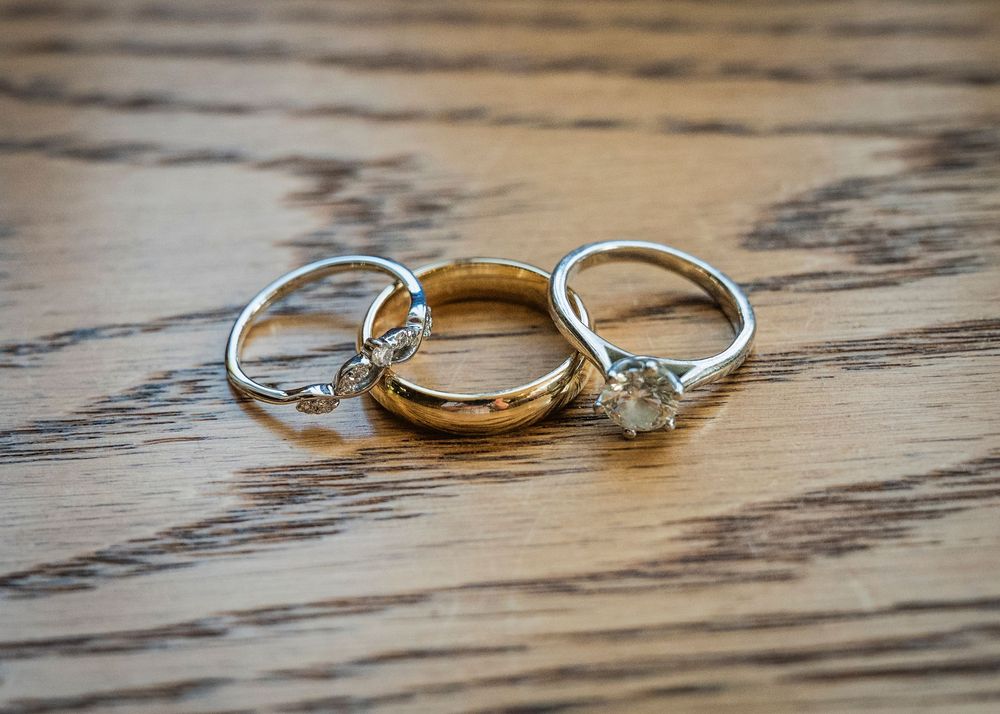 Close-up view of elegant wedding rings with diamonds arranged on rustic wooden surface in natural lighting.
