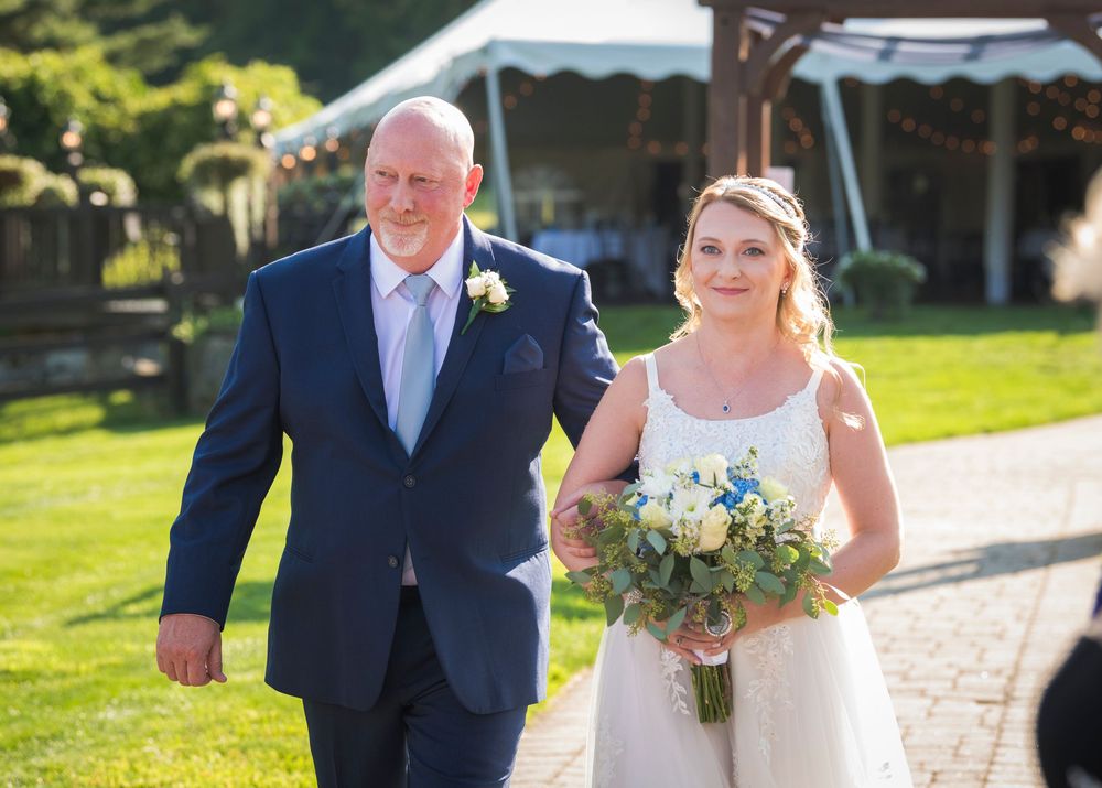 Members of wedding party stand in a sunny outdoor garden setting.