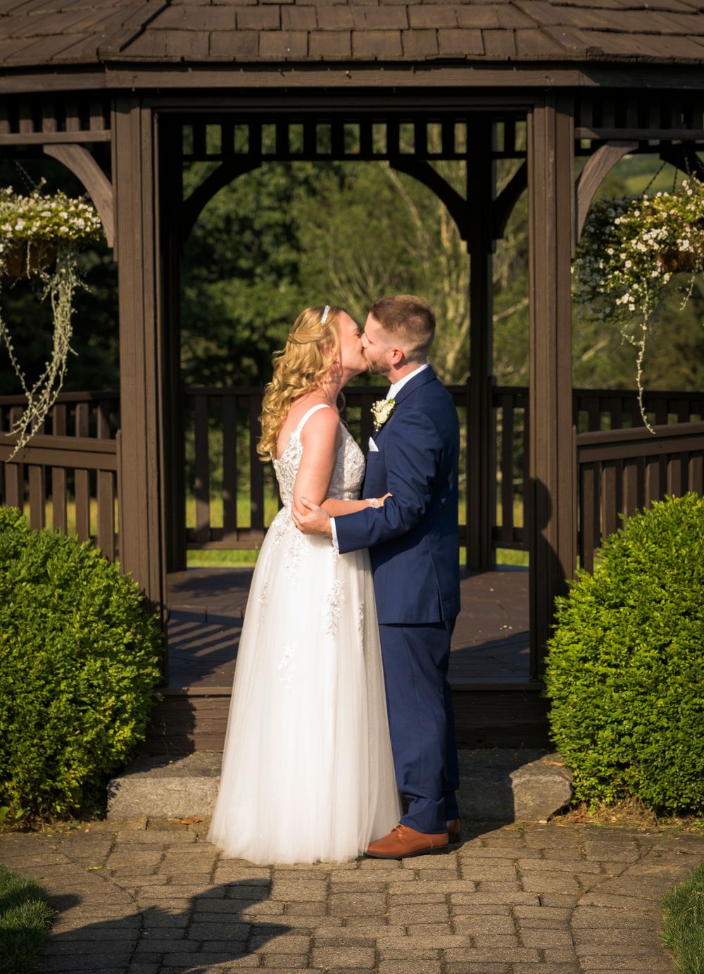Couple sharing romantic moments under wooden gazebo during sunset.