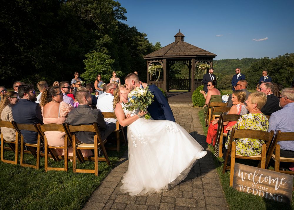 Outdoor wedding ceremony setup with wooden chairs and stone pathway overlooking scenic countryside views.