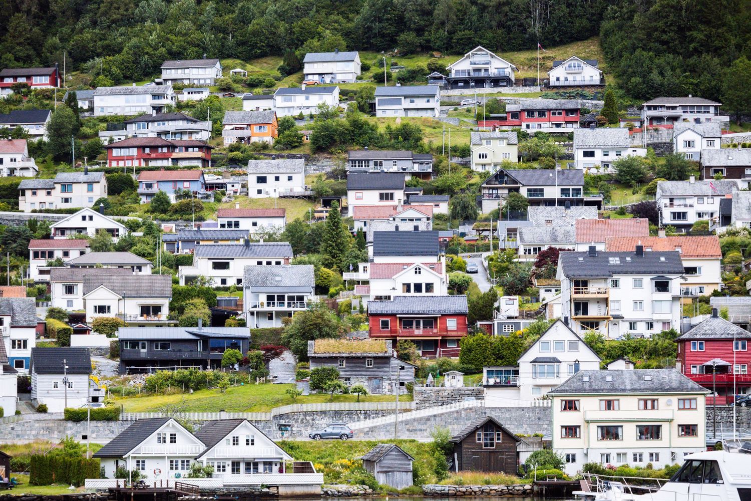 Colorful houses dot the hillside of a Norwegian coastal town with white and red buildings.