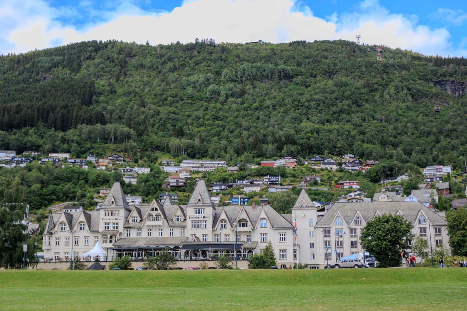 Victorian-style white hotel buildings nestled at the base of a forested mountain.