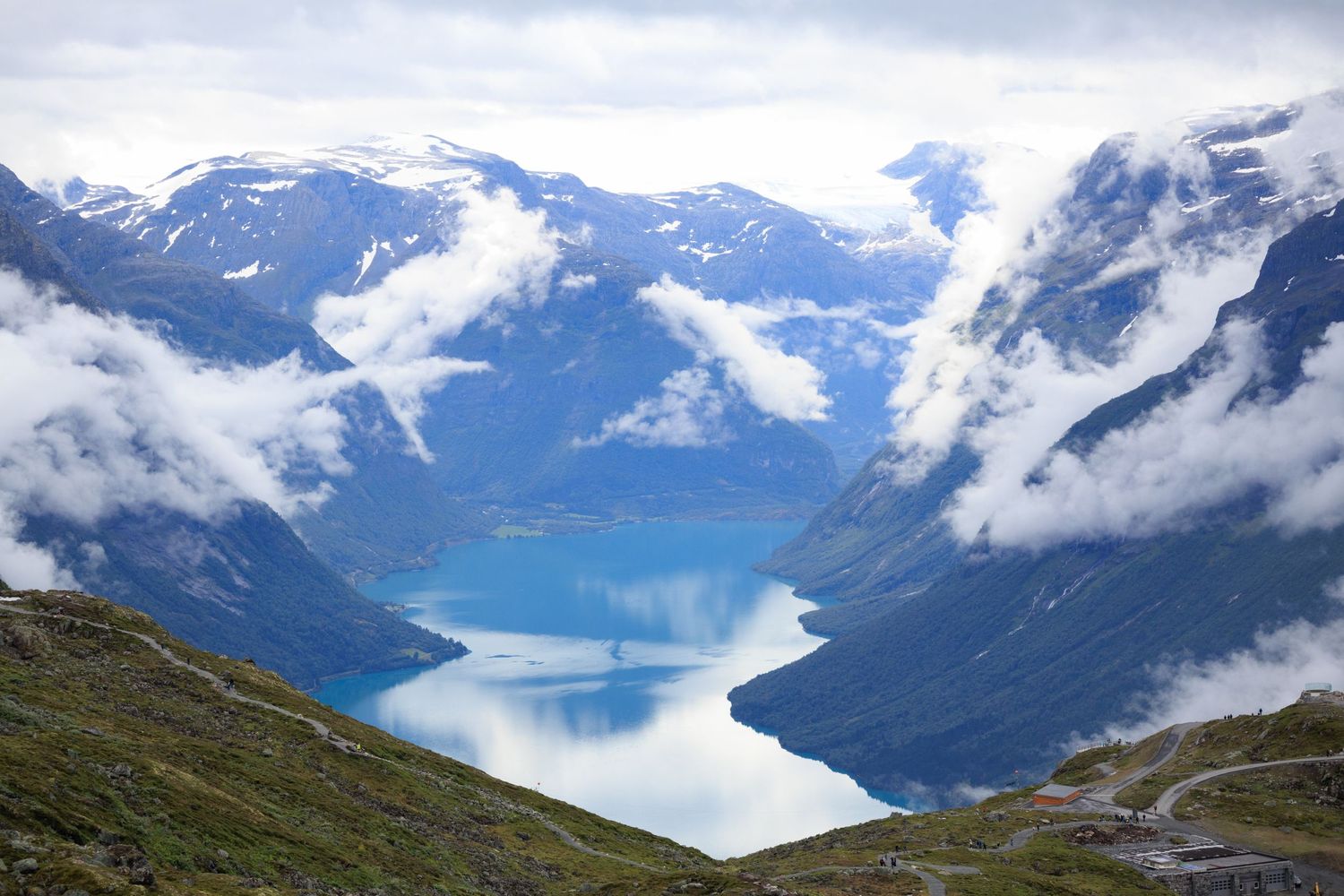 Stunning view of winding fjord surrounded by mountains with clouds rolling through valley.