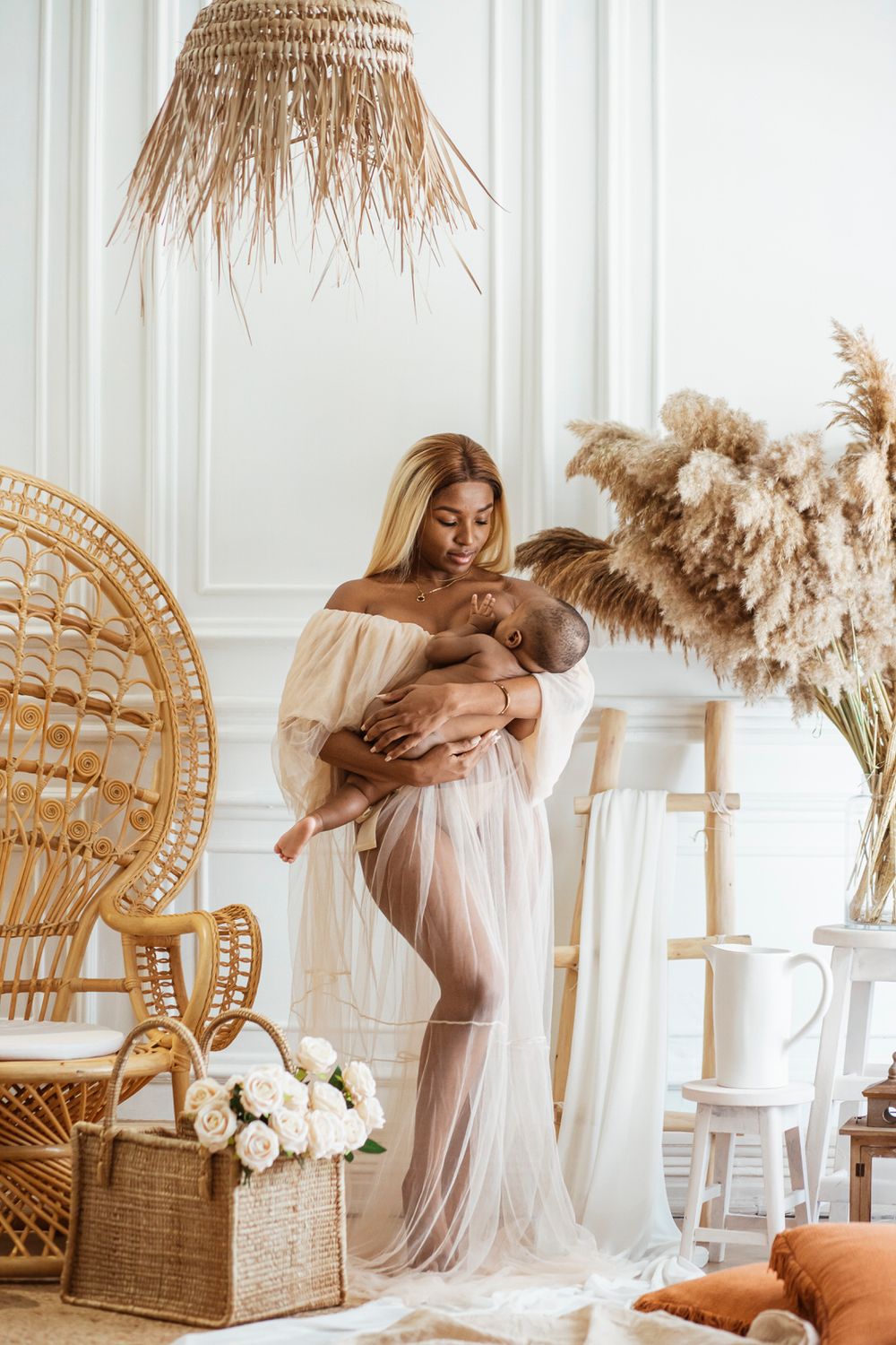 Dreamy boho nursery interior with peacock chair, pampas grass, and flowing sheer curtains in neutral earth tones.