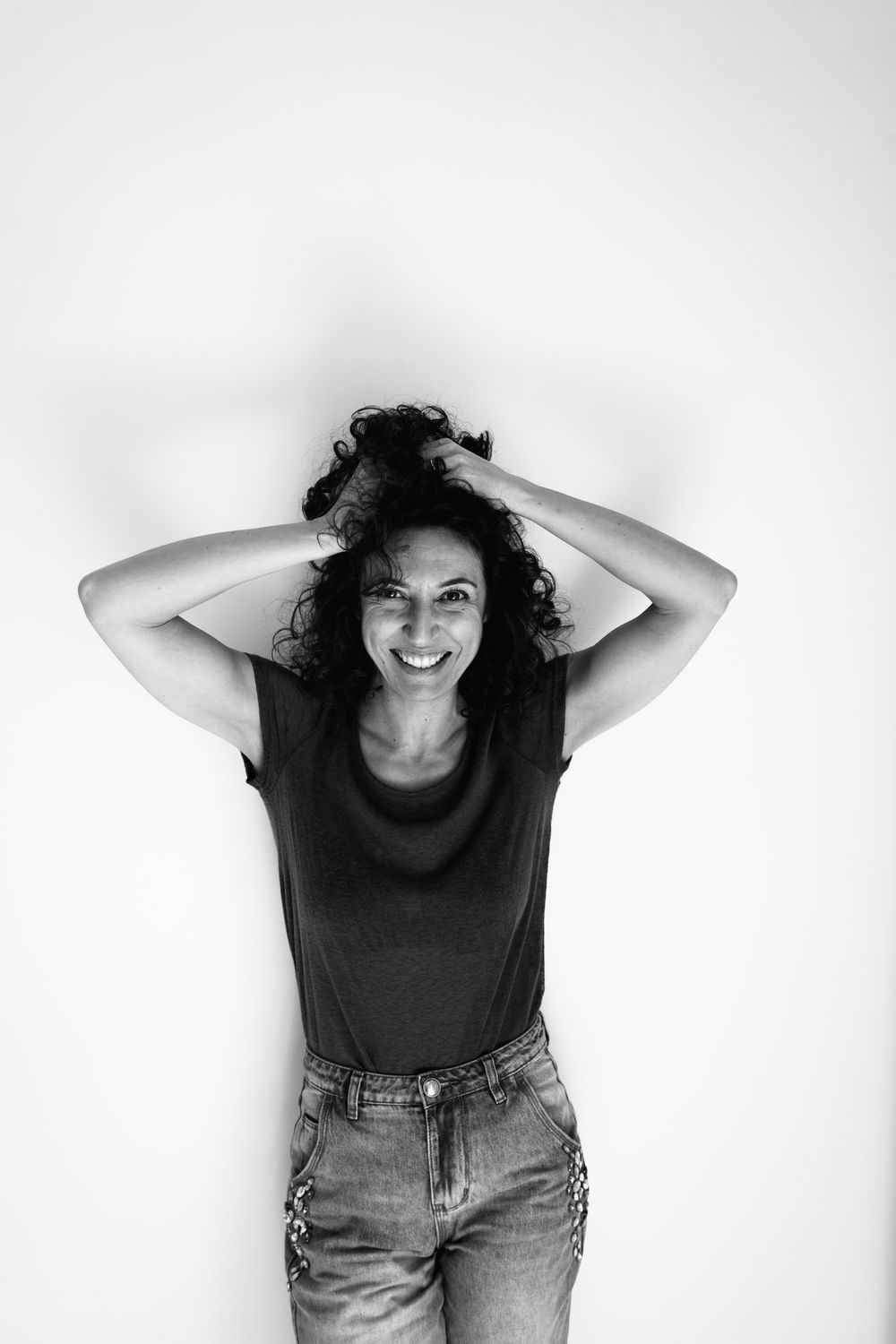 Black and white portrait series showing a person in casual attire with curly hair against a white background.
