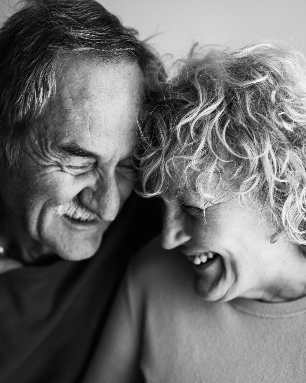 Black and white intimate portrait capturing a joyful shared moment of genuine laughter between two people.