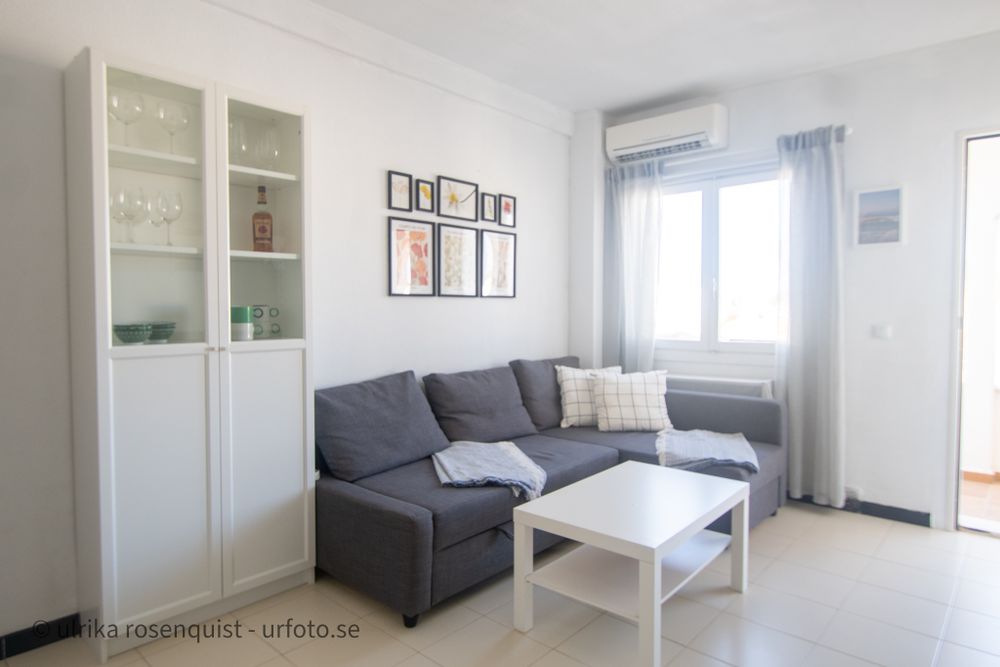 Modern bright living room with grey sectional sofa, white furniture and framed wall art.