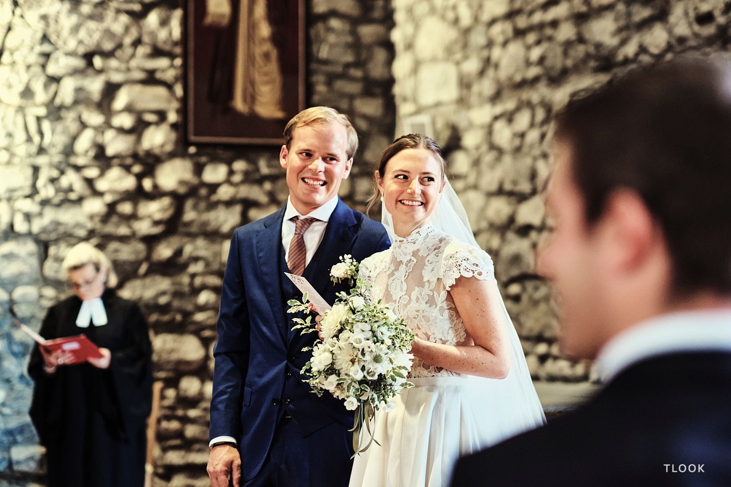 TLOOK photographe de mariage de style documentaire, à l'église les mariés sourient en regardant les invités