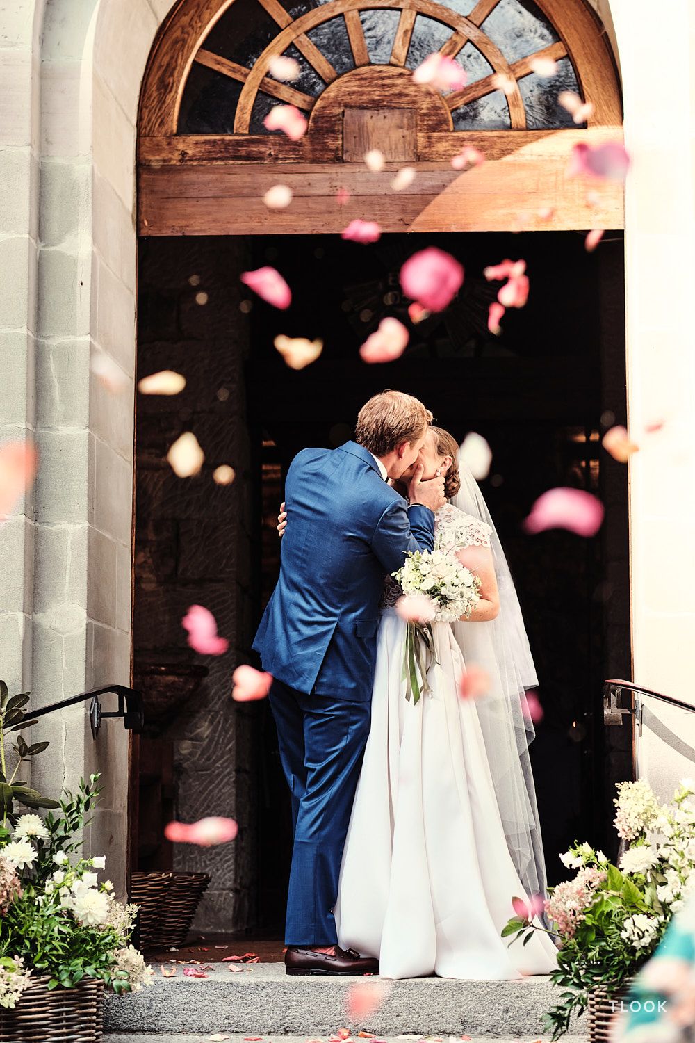 TLOOK photographe de mariage de style documentaire, les mariés sortent de l'église avec les pétales de fleurs