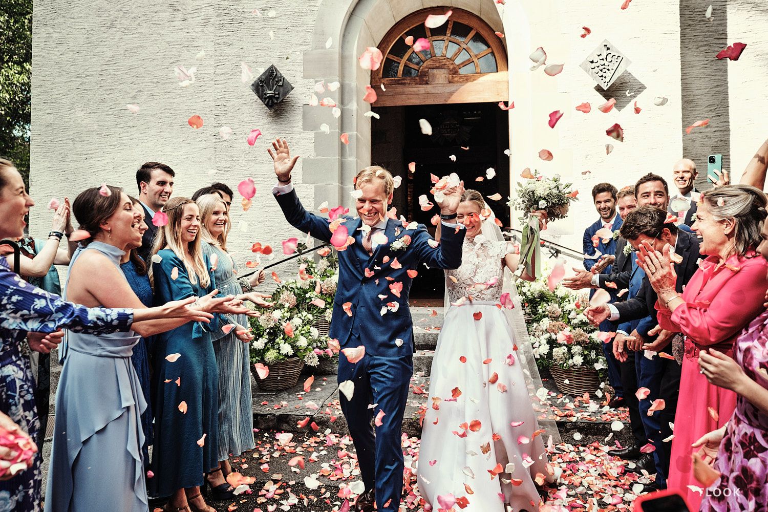 TLOOK photographe de mariage de style documentaire, les mariés sortent de l'église avec les pétales de fleurs