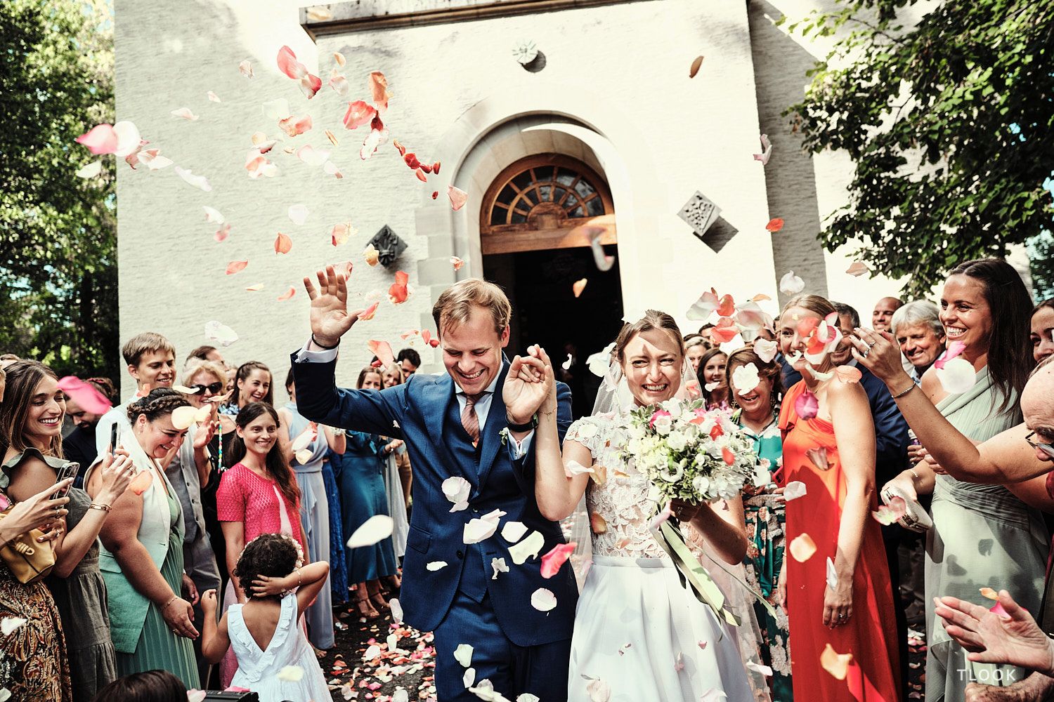 TLOOK photographe de mariage de style documentaire, les mariés sortent de l'église avec les pétales de fleurs