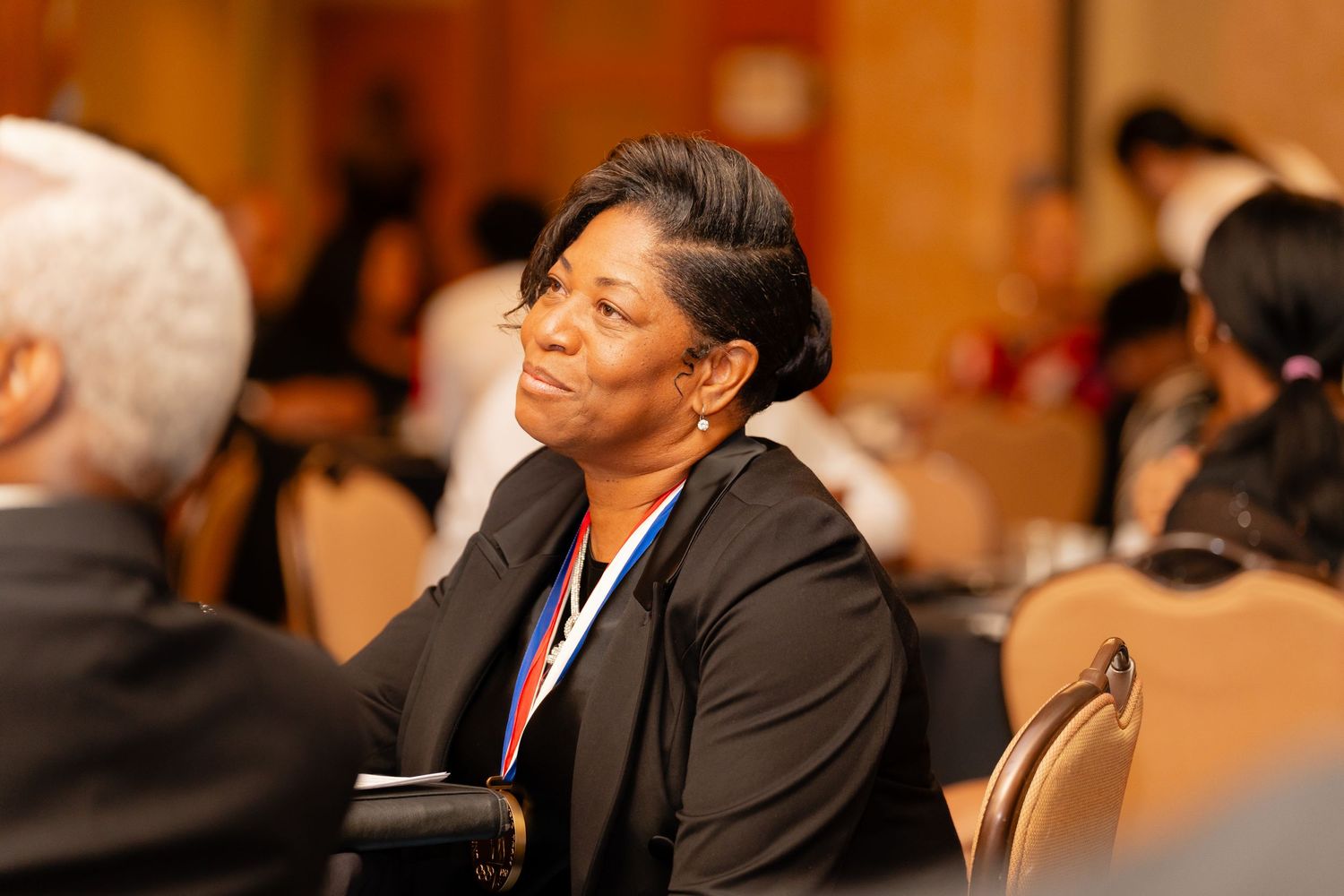 Professional attendee listening intently at a conference or business meeting in formal attire.