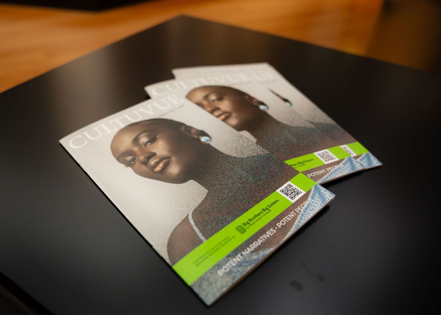 Printed graduation programs laying on dark surface with professional portraits.