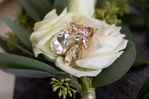 Sparkling crystal jewelry resting on a cream colored rose with green foliage.