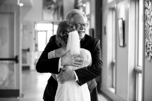 Emotional black and white candid moment in hallway during wedding celebration.