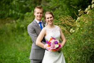 A romantic wedding portrait in a lush garden setting with vibrant pink bouquet.