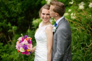 A romantic wedding moment captured against green garden foliage.
