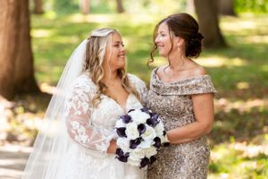 Joyful moment shared between two wedding attendees holding a navy and white bouquet.
