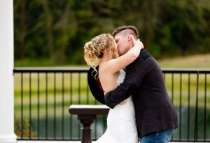 Romantic kiss between newlyweds on outdoor deck with railing.