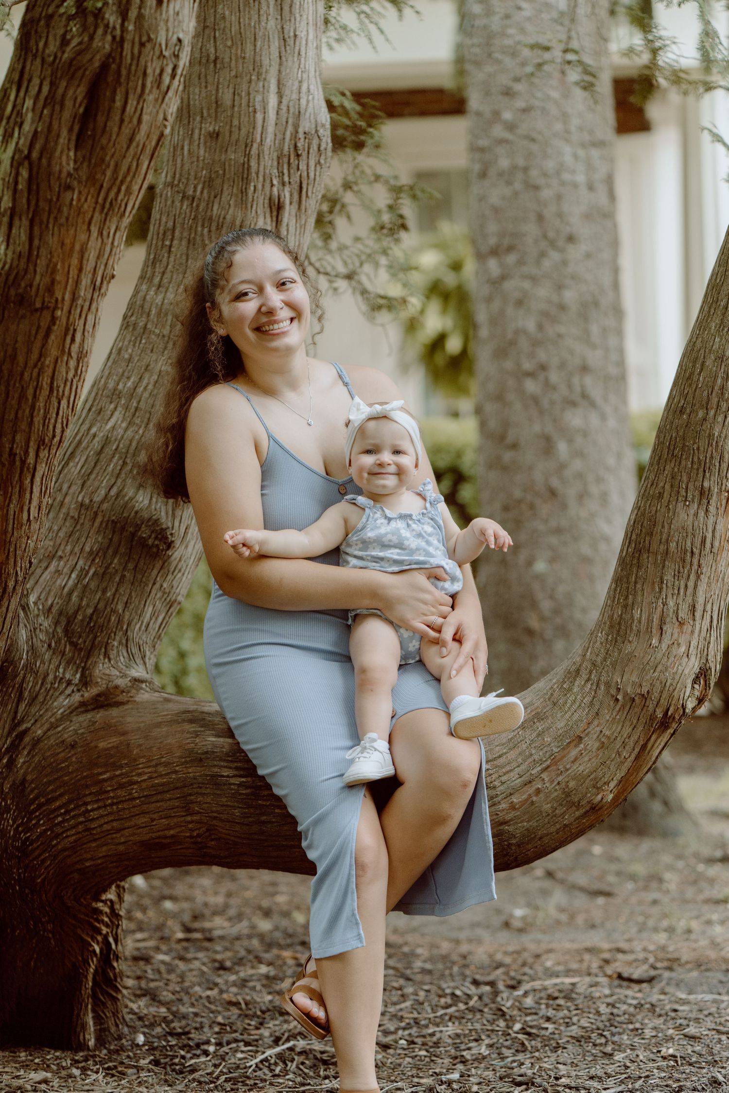 Joyful moment captured between parent and child playing by large tree trunks.