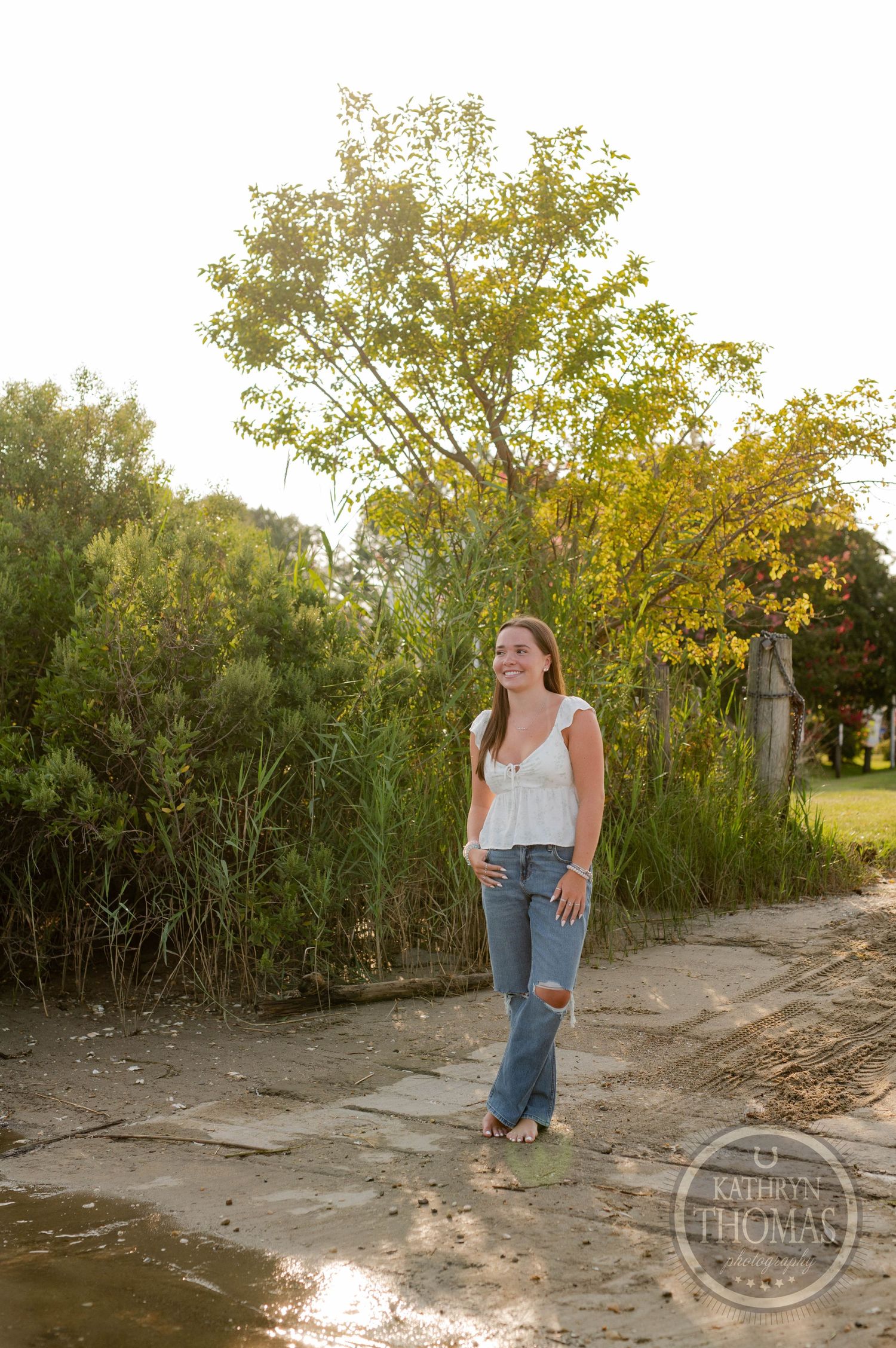 A portrait session along a sandy path with water reflections and tall grass.