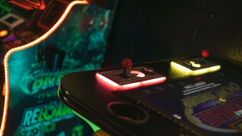 DJs mixing equipment illuminated with neon red and yellow lights on a dark nightclub turntable setup.