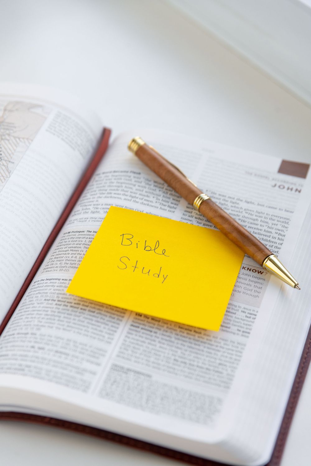 Open Bible with yellow sticky note labeled 'Bible Study' and gold pen for religious devotional time.