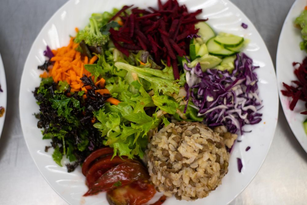 A colorful salad bowl with fresh vegetables including beets, carrots, cabbage, and lettuce arranged in sections.