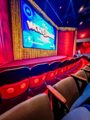 Interior view of Mickey Mouse-themed theater seats facing a large illuminated screen displaying Walt Disney VR experience.
