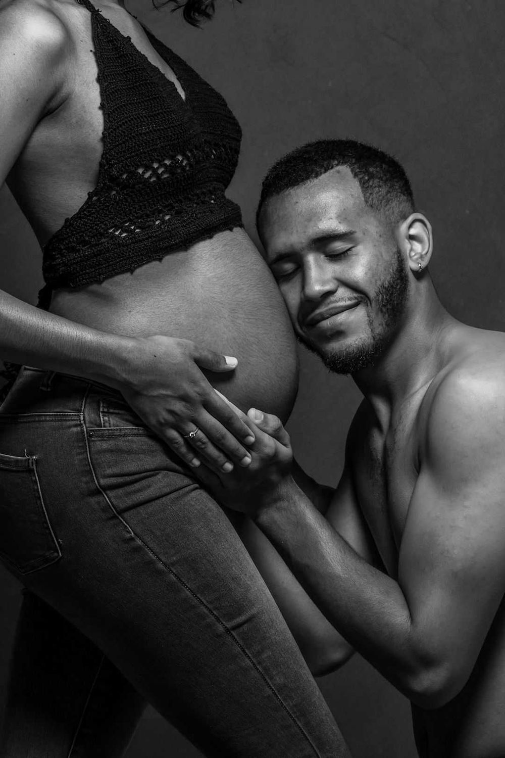 Black and white intimate maternity photo showing a tender moment as an expectant couple embrace.