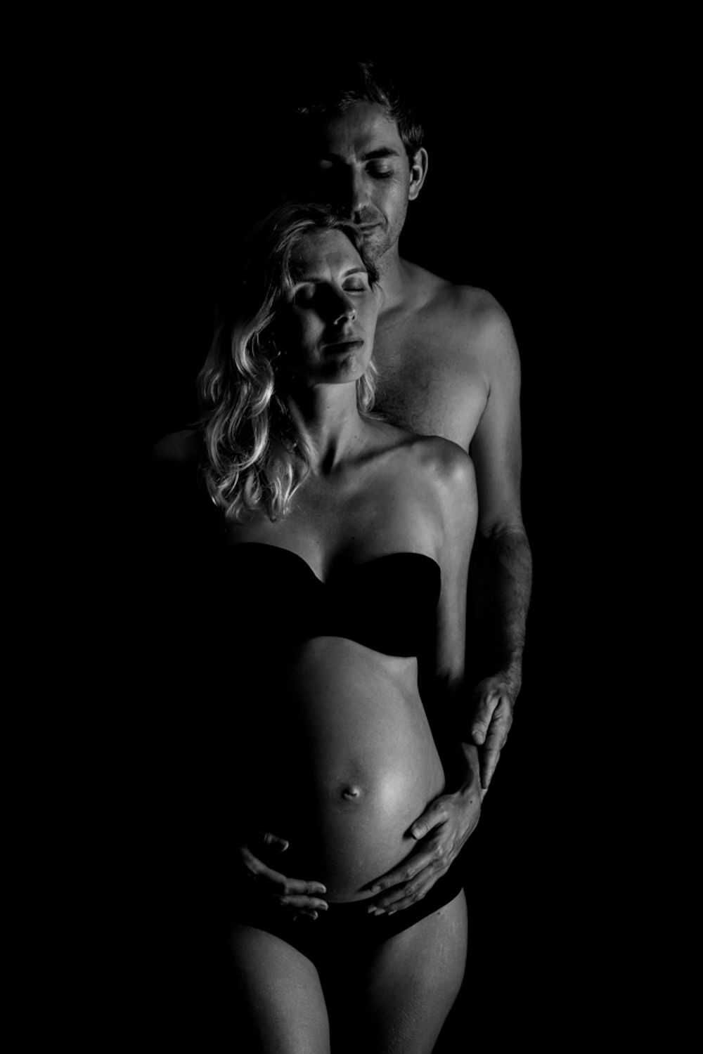 Artistic black and white intimate portrait of a couple in dramatic lighting and minimalist underwear.
