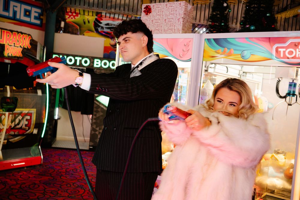 Bride and groom shooting with colourful arcade handguns in Weymouth during their New Year’s Eve wedding like the pulp fiction film poster