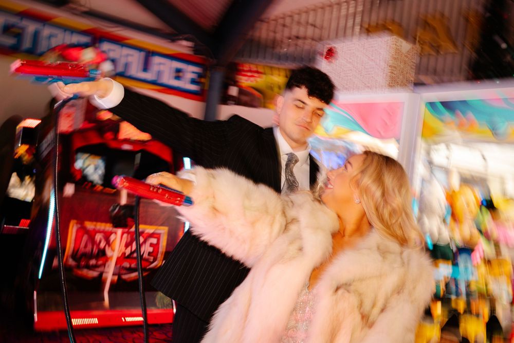 Bride and groom holding colourful arcade handguns in Weymouth during their New Year’s Eve wedding