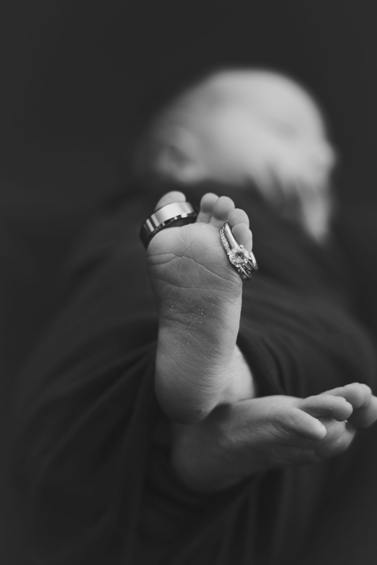 Black and white artistic photo series showing tiny baby feet with rings delicately placed on their toes.