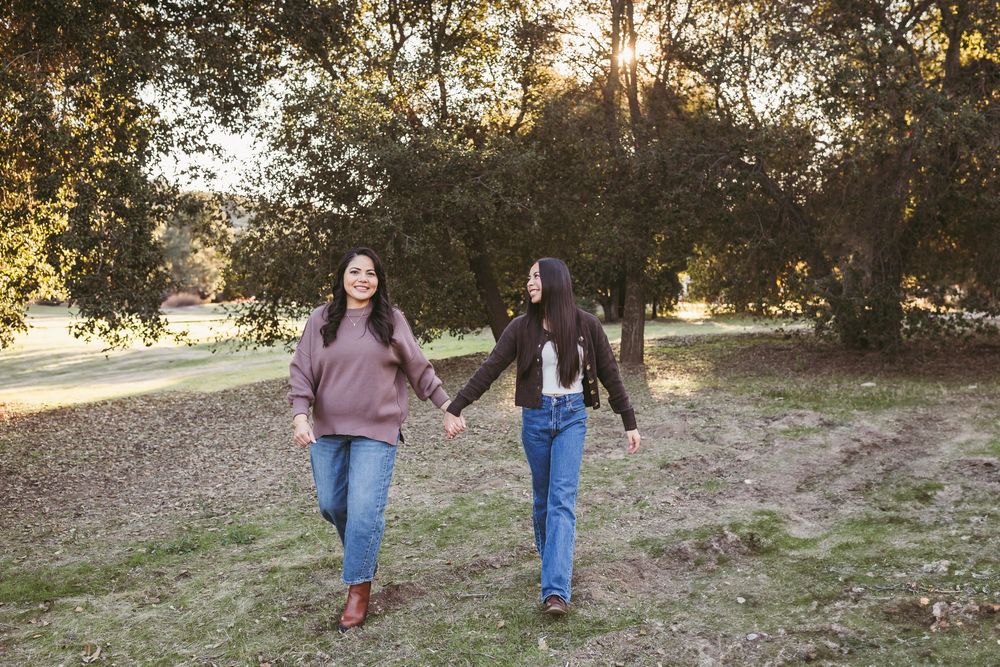 Two friends walking together holding hands in a park during golden hour sunset.