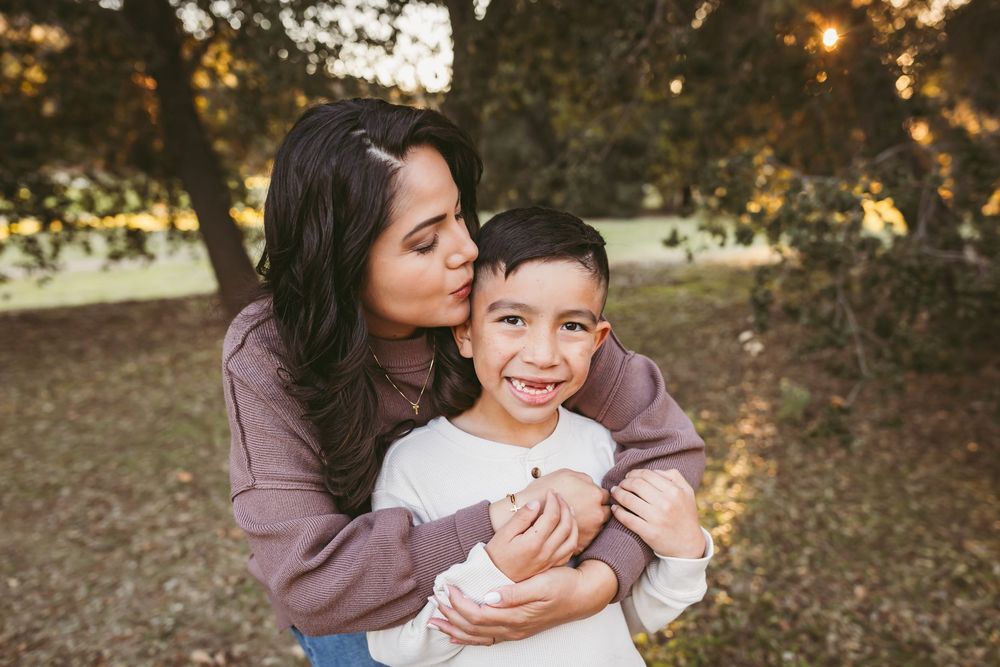 A loving embrace between parent and child outdoors during golden hour with warm sunset lighting in the background.