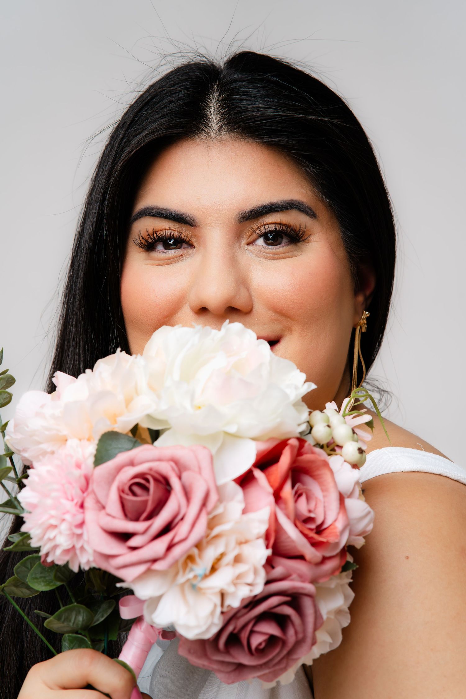 Person smiling while holding a bouquet of white tulips in a park on a sunny day.