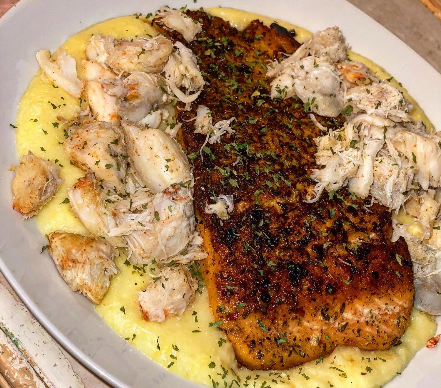 Grilled fish fillets served on a bed of yellow rice with fresh herbs and seasonings.