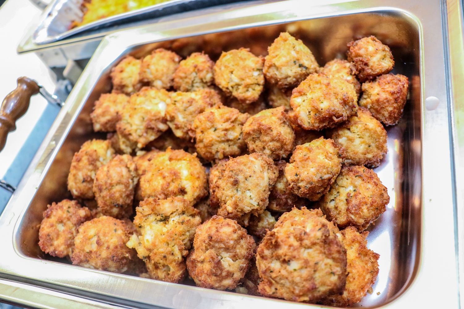Golden brown meatballs arranged in metal serving trays.