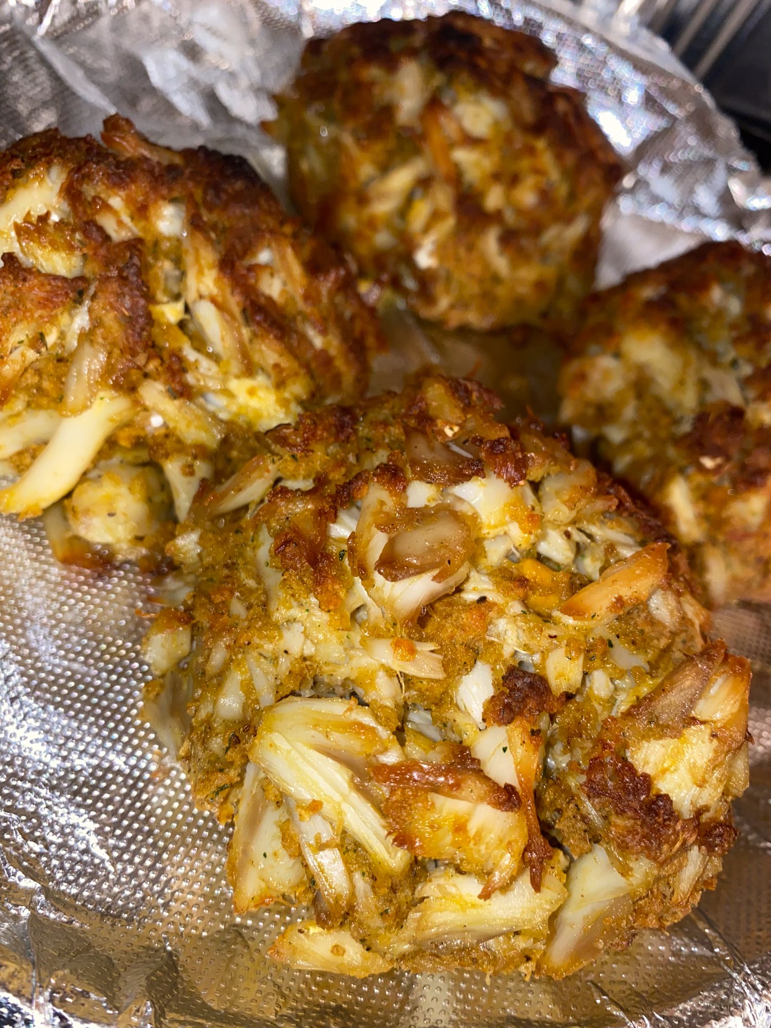 Garlic bread covered in melted cheese and herbs on aluminum foil.